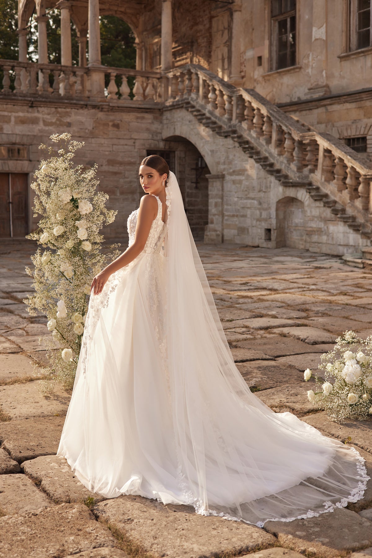 Back view of an ivory wedding dress with lace detailing, a sheer veil, and an extended flowing train