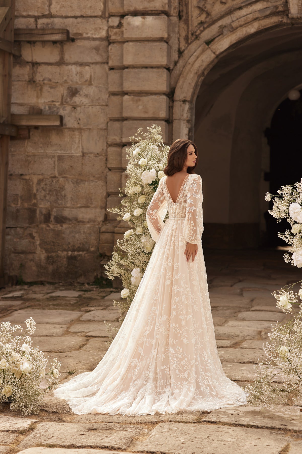Ivory wedding dress shown from the back with long lace sleeves, a sheer lace back, and a sweeping train