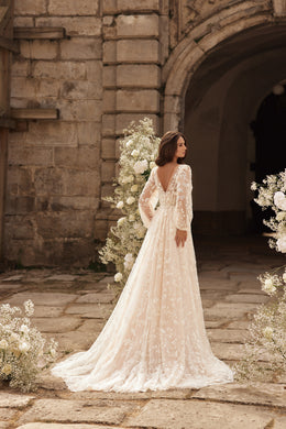 Ivory wedding dress shown from the back with long lace sleeves, a sheer lace back, and a sweeping train
