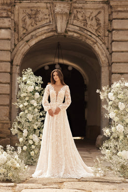 Ivory A-line wedding dress with long sheer lace sleeves, floral appliqués, and a flowing floor-length skirt