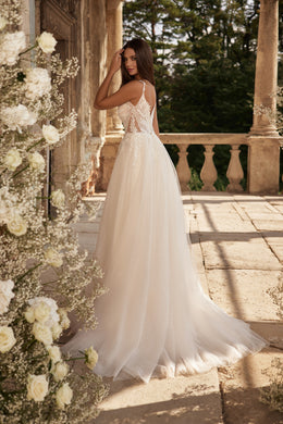 Ivory wedding dress with a low open back, thin straps, floral lace detailing, flowing A-line skirt, and train