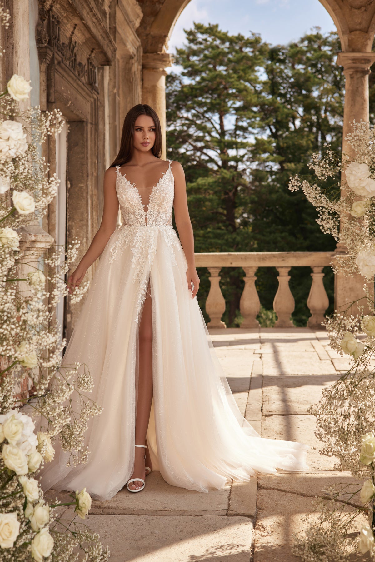 Ivory A-line wedding dress with a deep V-neck, floral lace bodice, high front slit, and sweeping train
