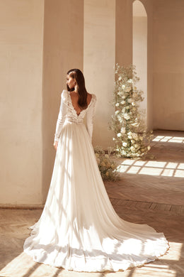Ivory wedding dress with a deep V lace back, long sleeves, flowing skirt, and sweeping train