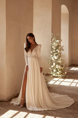 Ivory wedding dress with a plunging V-neck lace bodice, long sleeves, high slit, and train