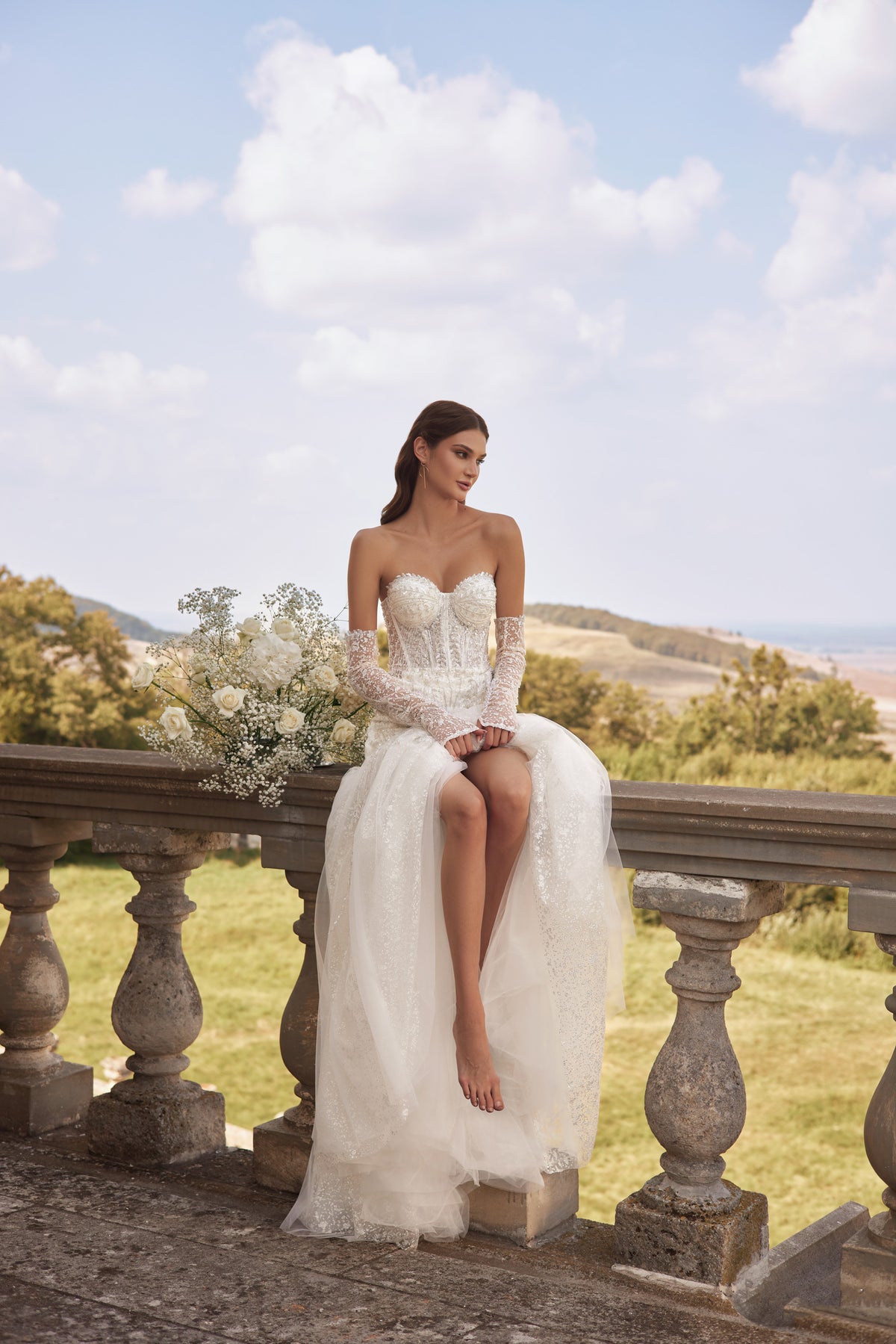 Ivory mermaid wedding dress with a sweetheart neckline, lace sleeves, beaded bodice, and thigh-high slit