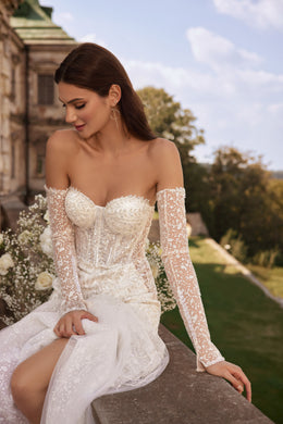 Close-up of an ivory wedding dress with a sweetheart neckline, sheer floral lace sleeves, and beaded corset bodice