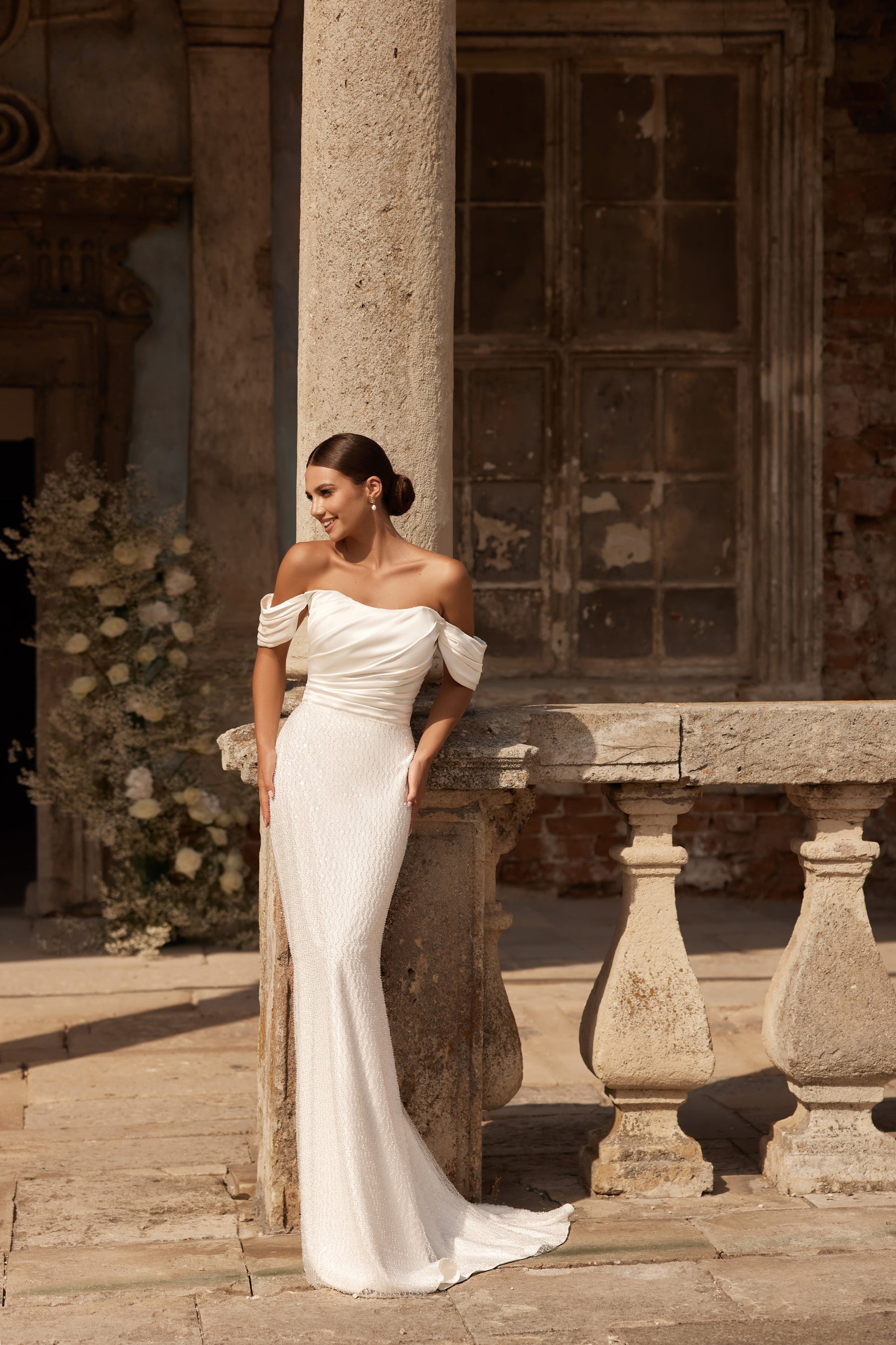 Ivory mermaid wedding dress with an off-the-shoulder neckline, draped sleeves, and a long train