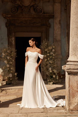 Ivory wedding dress with a fitted beaded skirt, off-the-shoulder sleeves, and a flowing overskirt