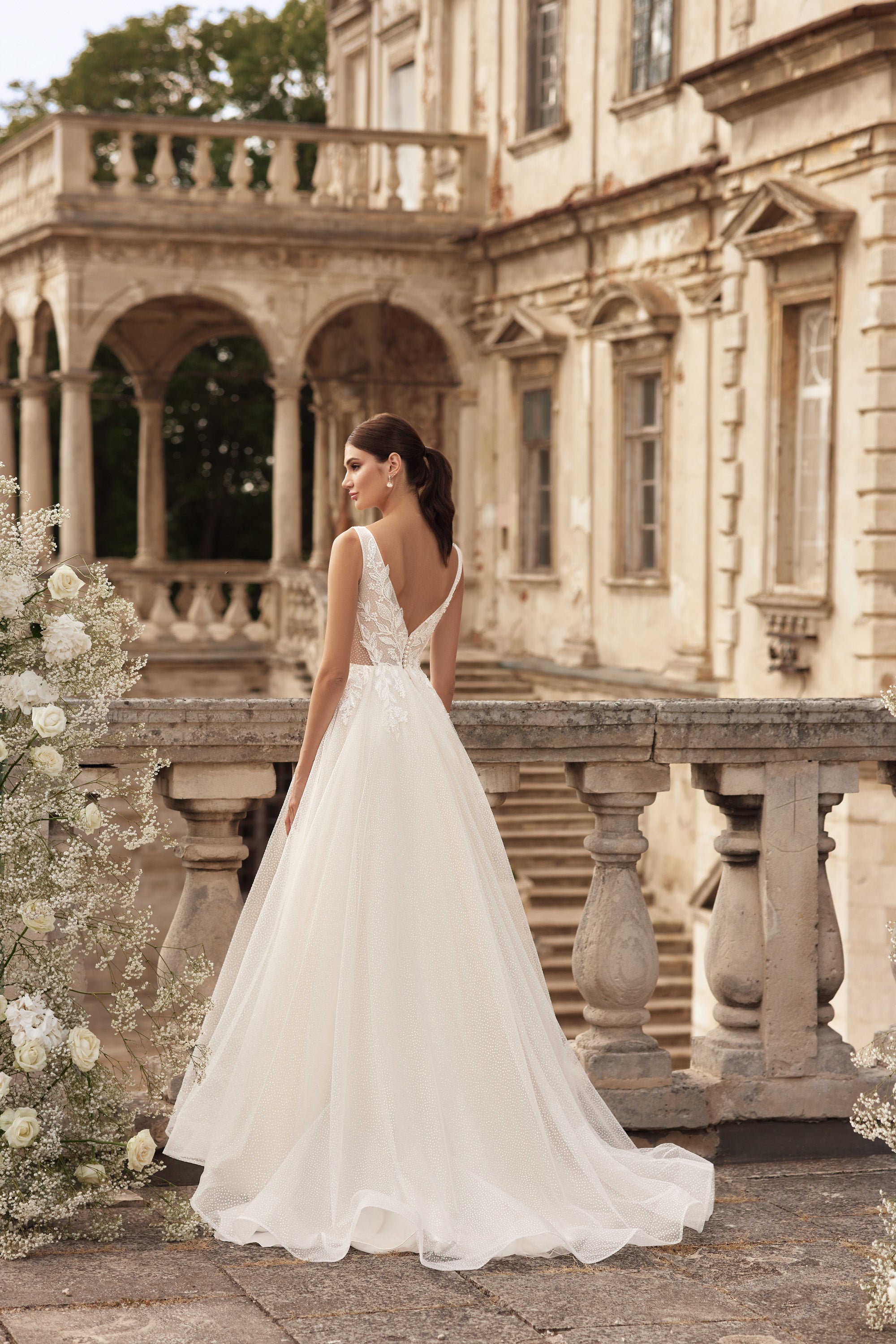 Ivory wedding dress with a deep V-back, sleeveless design, full A-line skirt, and sweeping train