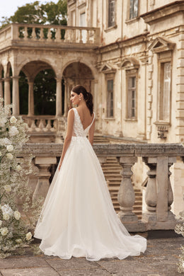 Ivory wedding dress with a deep V-back, sleeveless design, full A-line skirt, and sweeping train