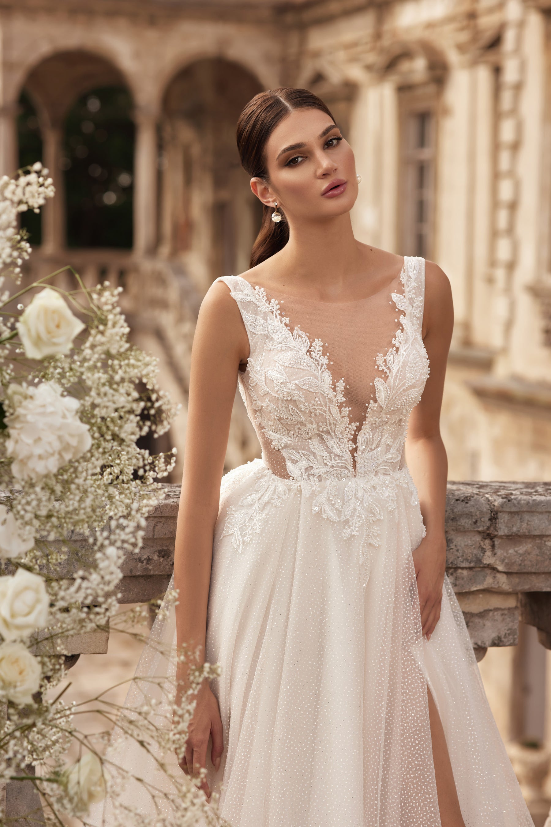 Close-up of an ivory wedding dress bodice with sheer V-neckline and floral lace appliqués