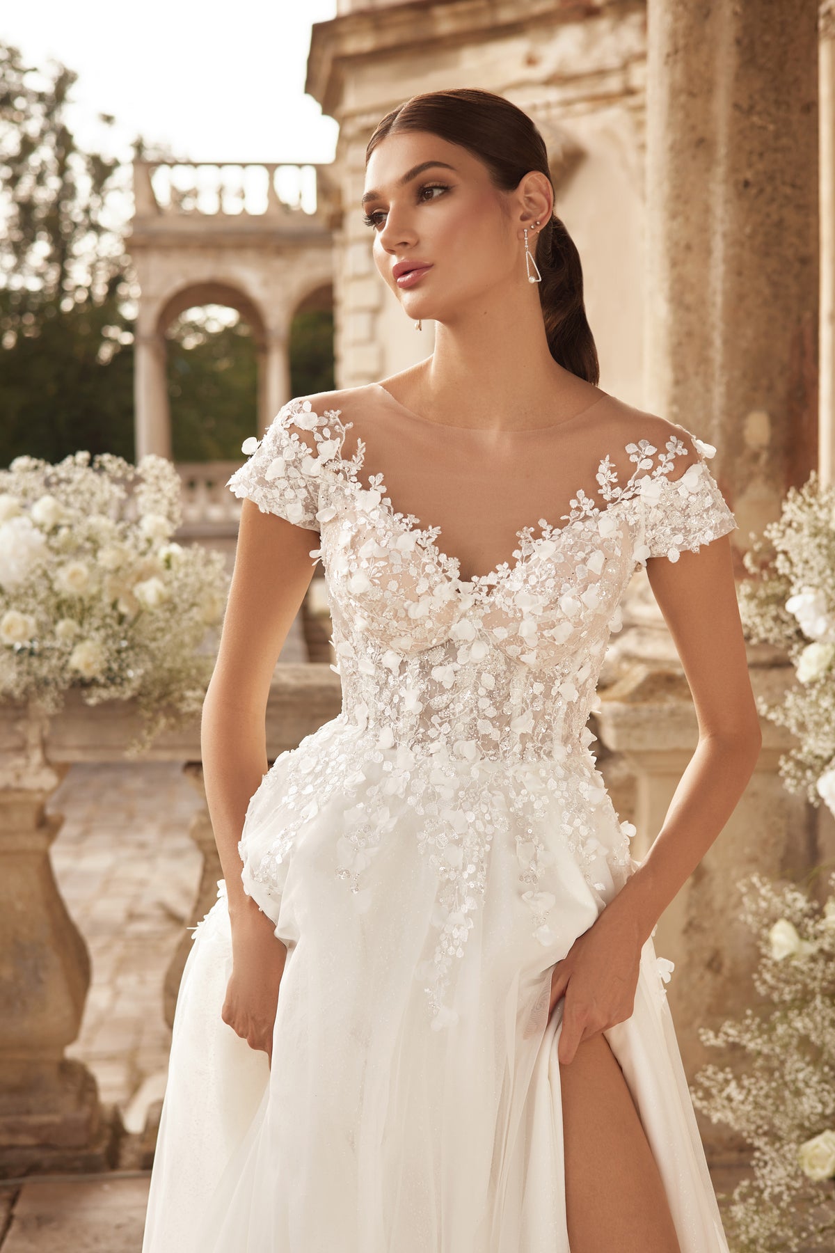 Floral lace illusion bodice and plunging neckline on an ivory wedding dress with a dramatic thigh-high slit