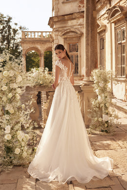 Flowing ivory wedding dress with a long train, floral lace back, and sheer cap sleeves