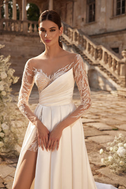 Ivory wedding dress with asymmetric draped bodice, sheer floral lace sleeves, and a thigh-high slit