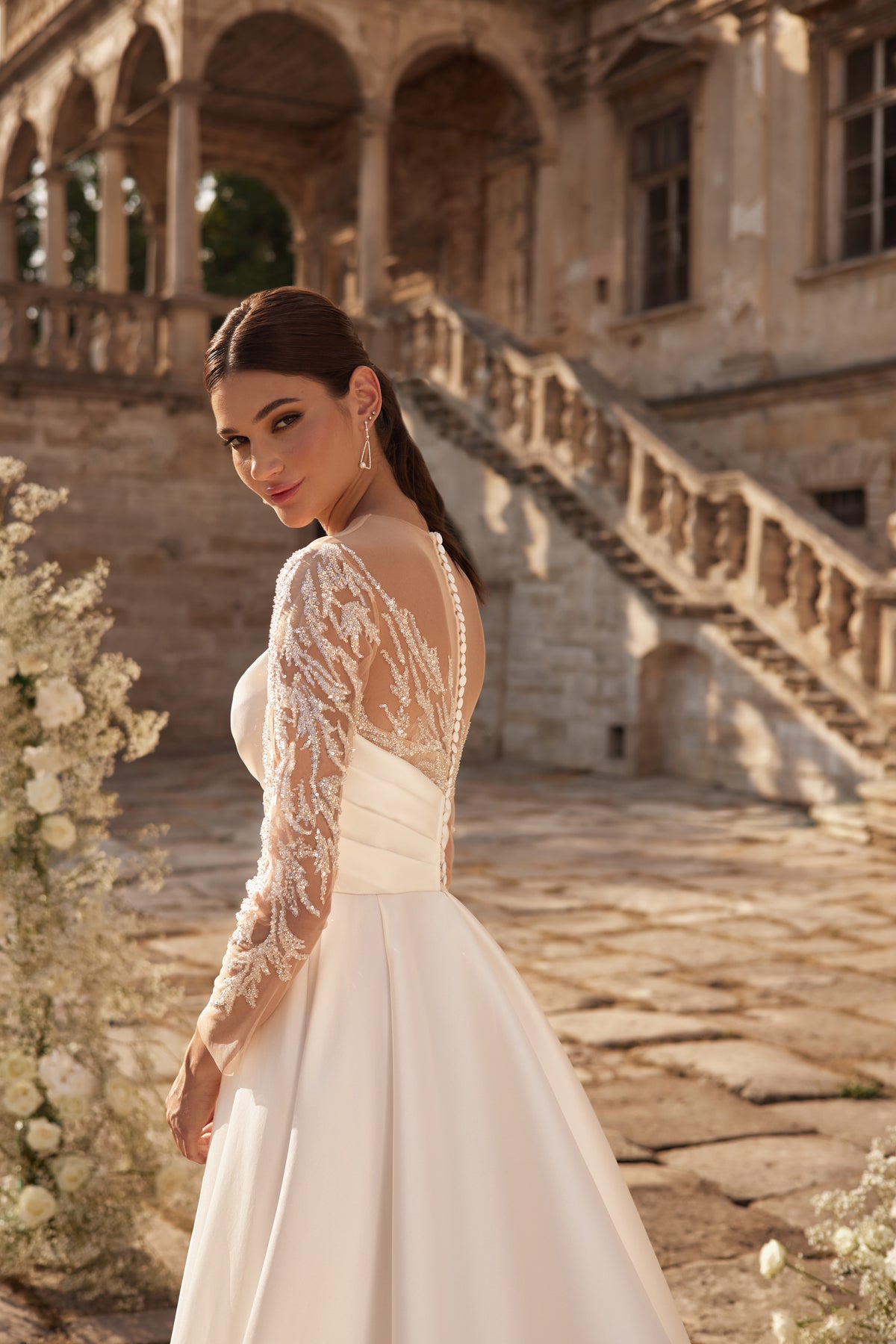Sheer floral lace back and long sleeves on an ivory wedding dress with a flowing skirt