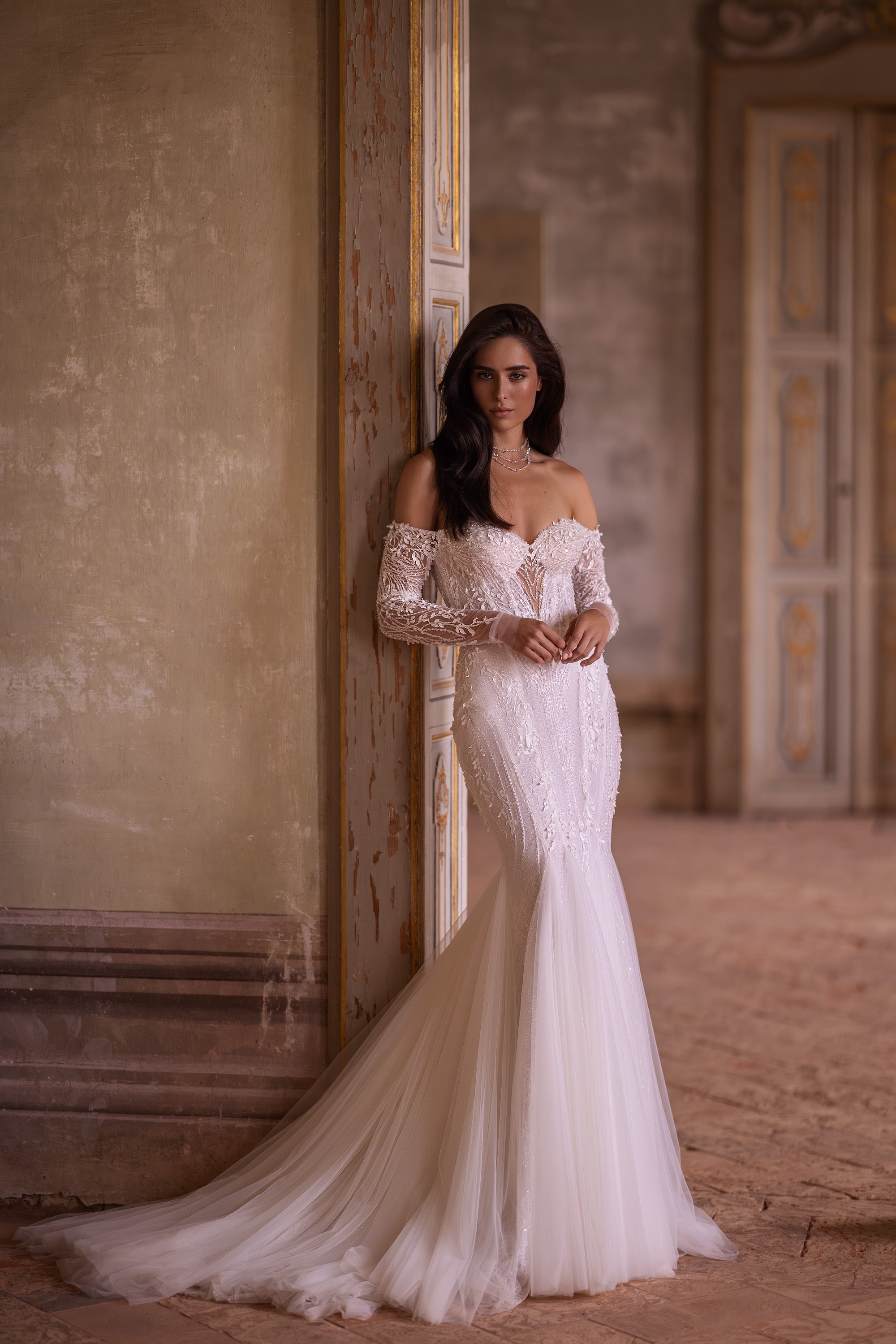 Ivory mermaid wedding dress with long lace sleeves, off-the-shoulder neckline, and an extended train