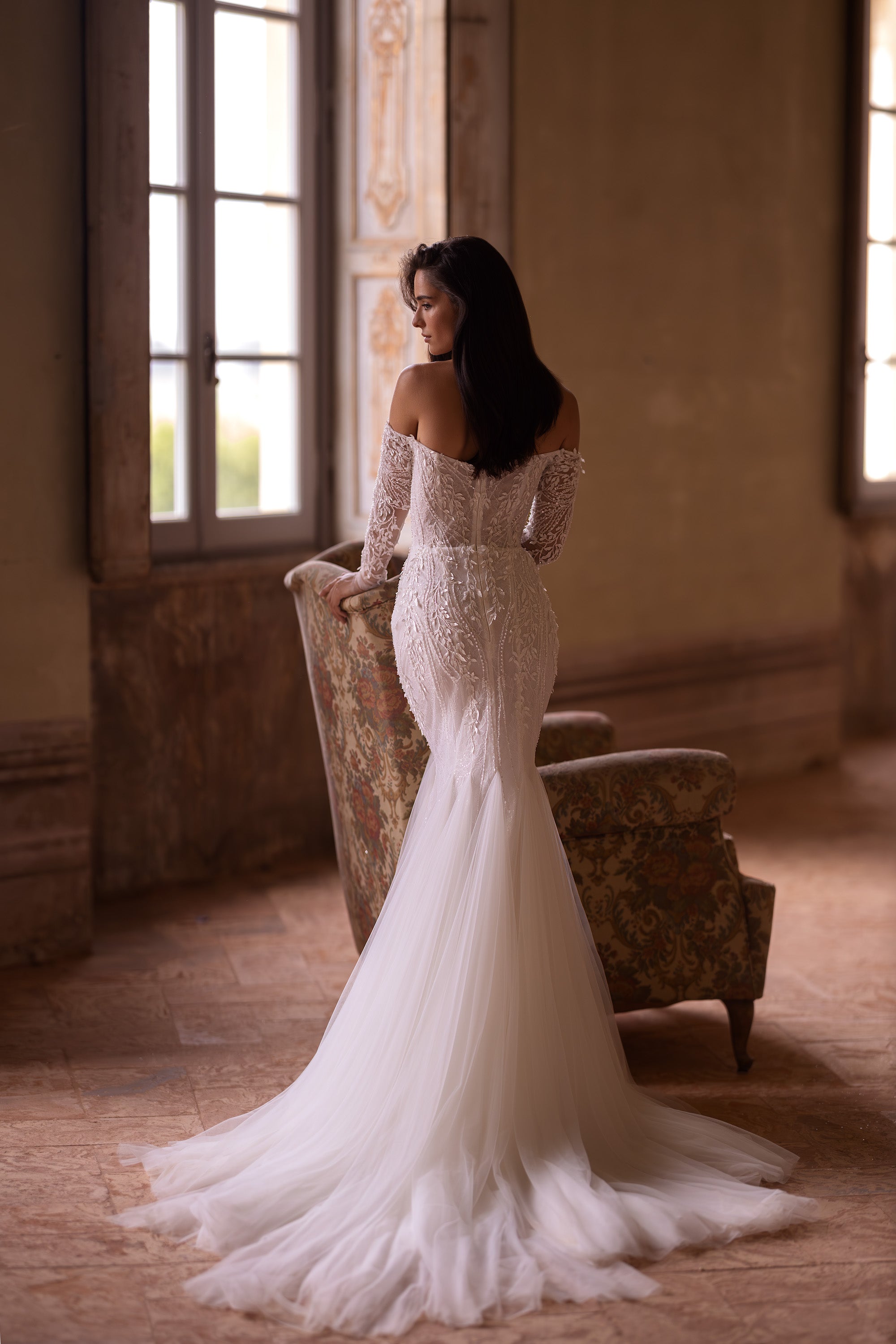 Lace-back ivory wedding dress with a fitted mermaid silhouette, long sleeves, and a flowing train