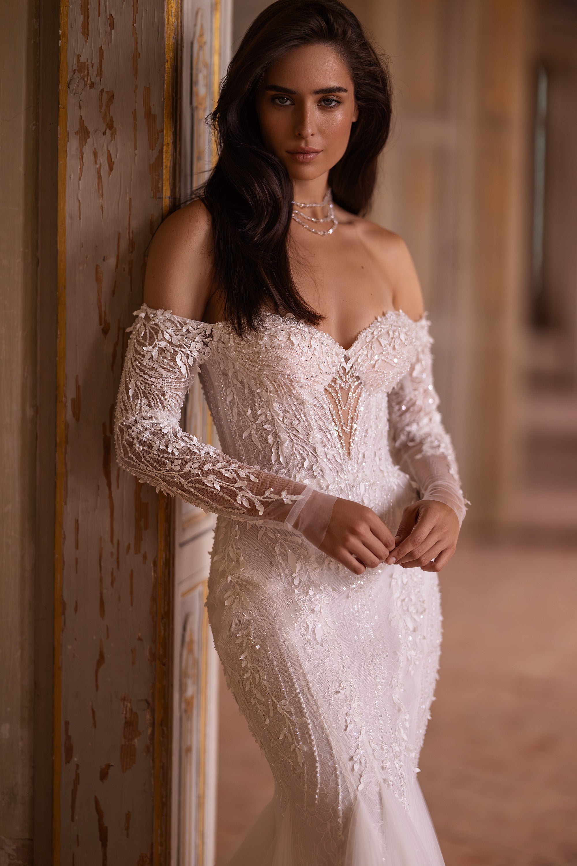 Close-up of floral lace appliqués, sweetheart neckline, and sheer long sleeves on an ivory wedding dress