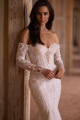 Close-up of floral lace appliqués, sweetheart neckline, and sheer long sleeves on an ivory wedding dress
