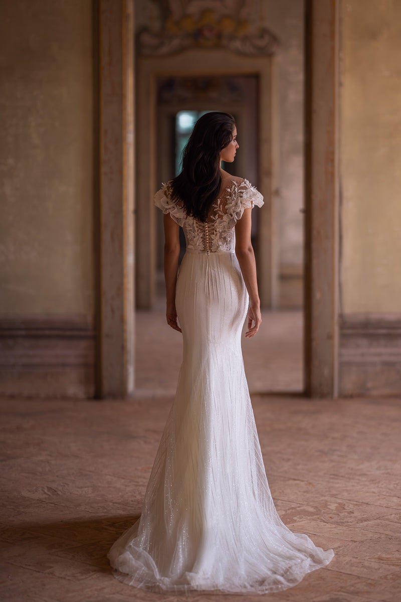 Ivory wedding dress with a sheer floral-lace back, covered buttons, fitted skirt, and train