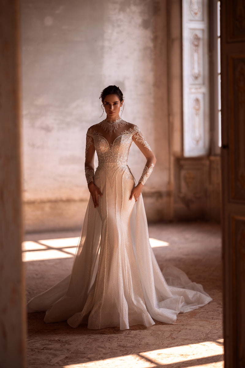 Shimmering ivory mermaid wedding dress with an illusion neckline, long sleeves, and a sweeping train