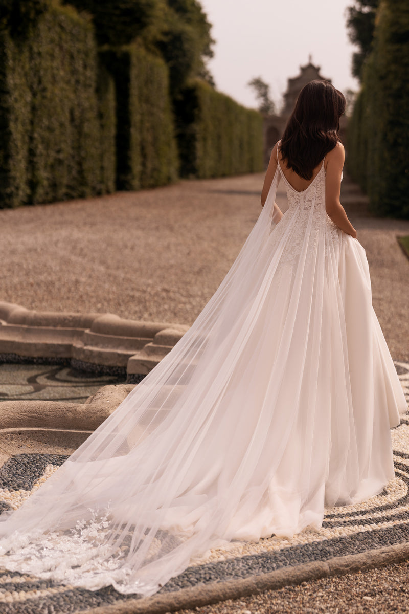 Low V-back and flowing sheer train on an ivory A-line wedding dress with delicate lace detailing