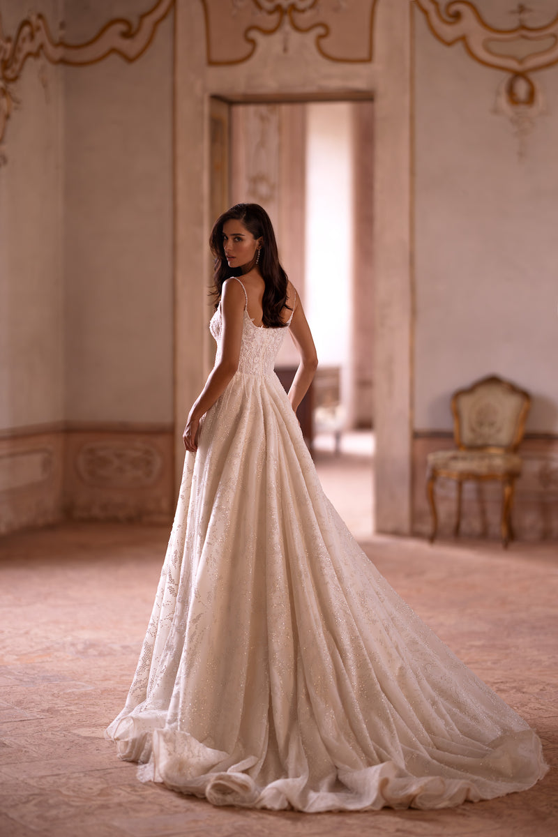 Glittering ivory wedding dress with slender straps, a defined waist, full A-line skirt, and sweeping train