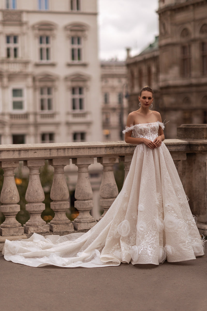 Ivory ball gown wedding dress with an off-the-shoulder neckline, floral appliqués, and a long train