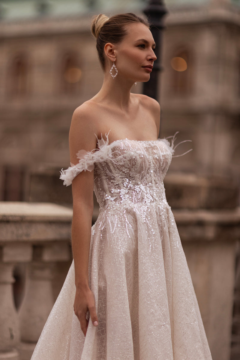 Close-up of an ivory wedding dress with sparkling floral appliqués and an off-the-shoulder neckline
