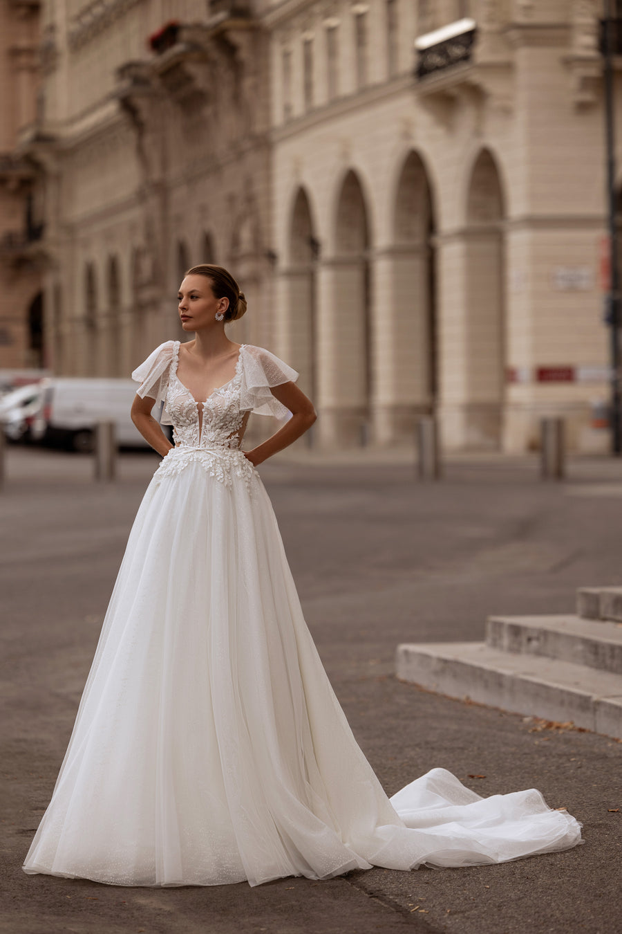 A-line ivory wedding dress with ruffled cap sleeves, floral lace bodice, and flowing train