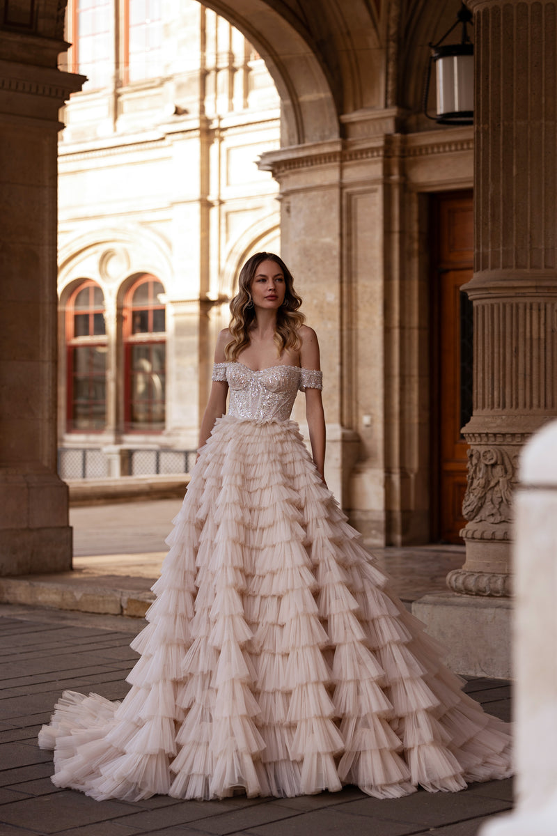 Ivory ball gown wedding dress with an off-shoulder crystal bodice and tiered ruffled skirt