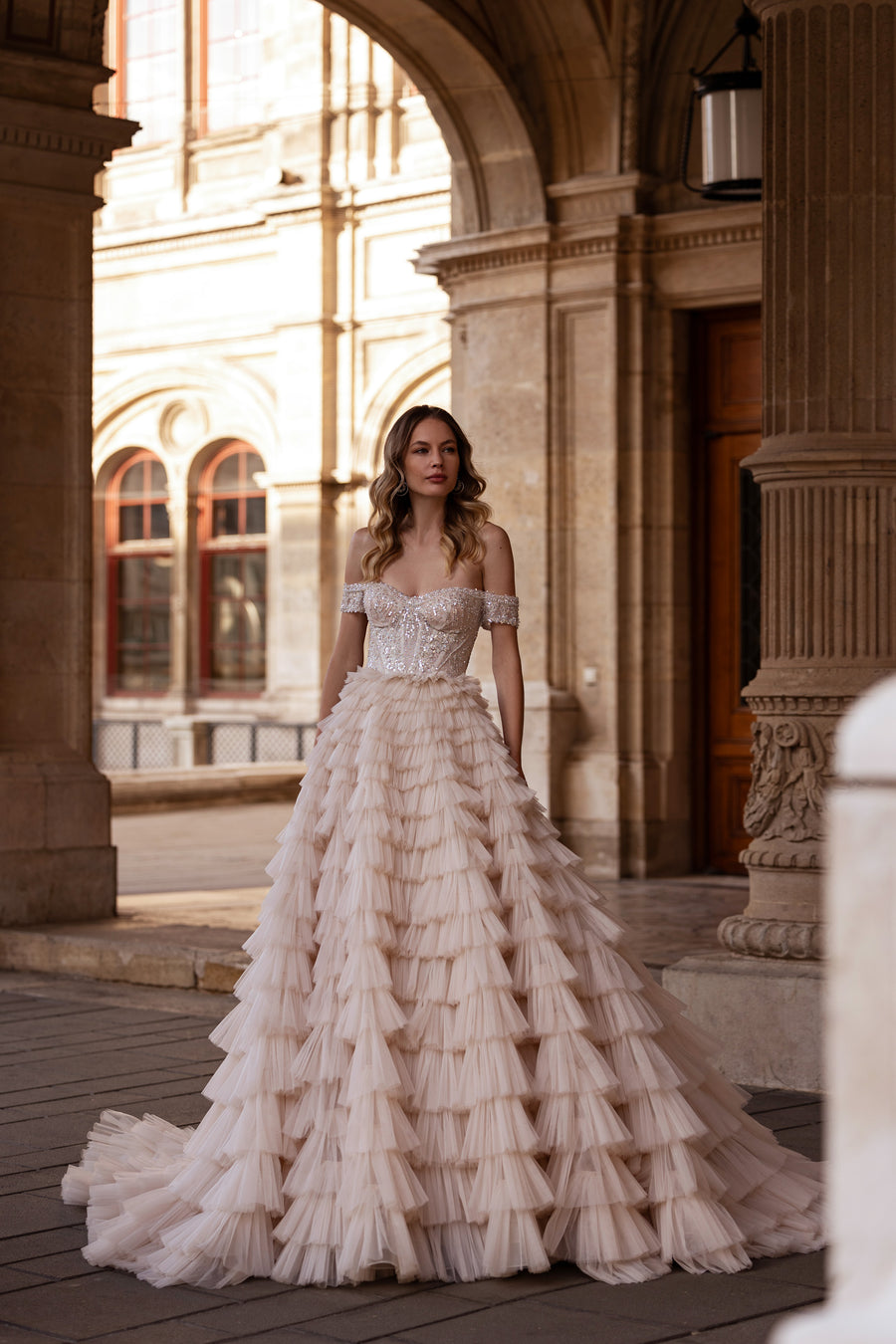 Ivory ball gown wedding dress with an off-shoulder crystal bodice and tiered ruffled skirt