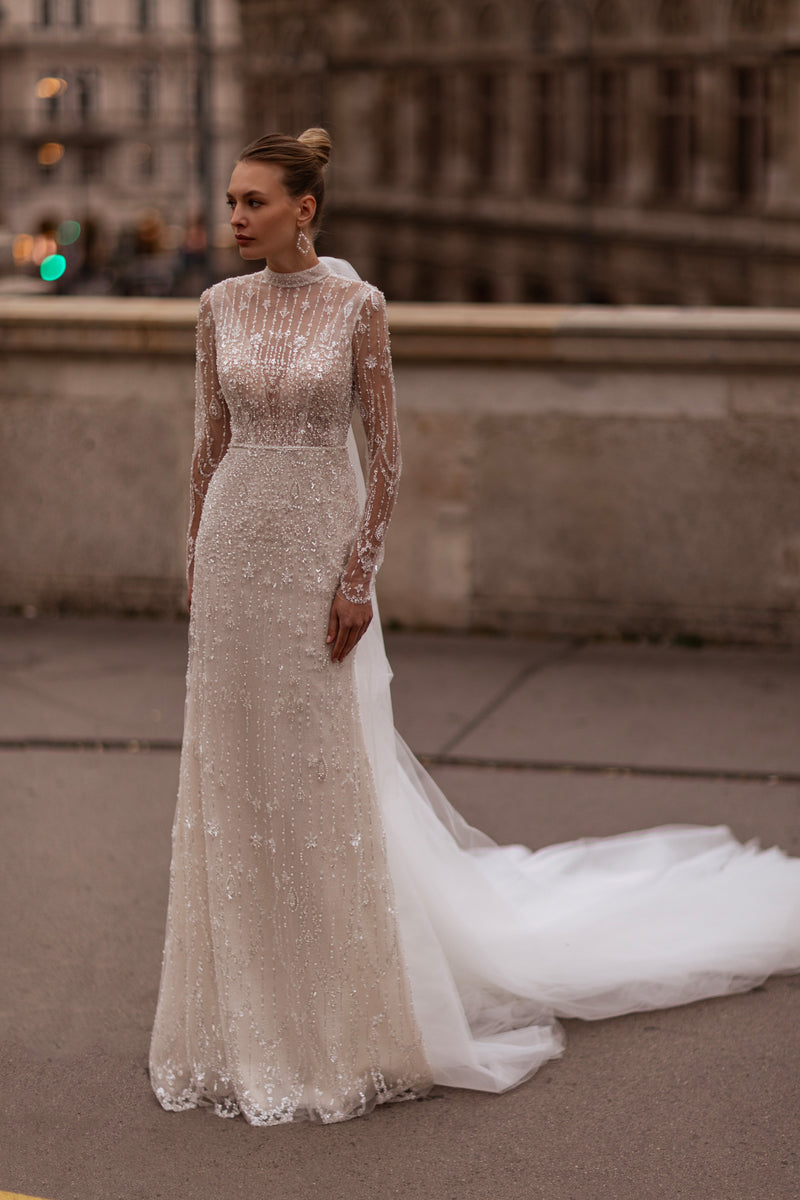 Ivory beaded wedding dress with a high illusion neckline, sheer long sleeves, fitted skirt, and flowing train