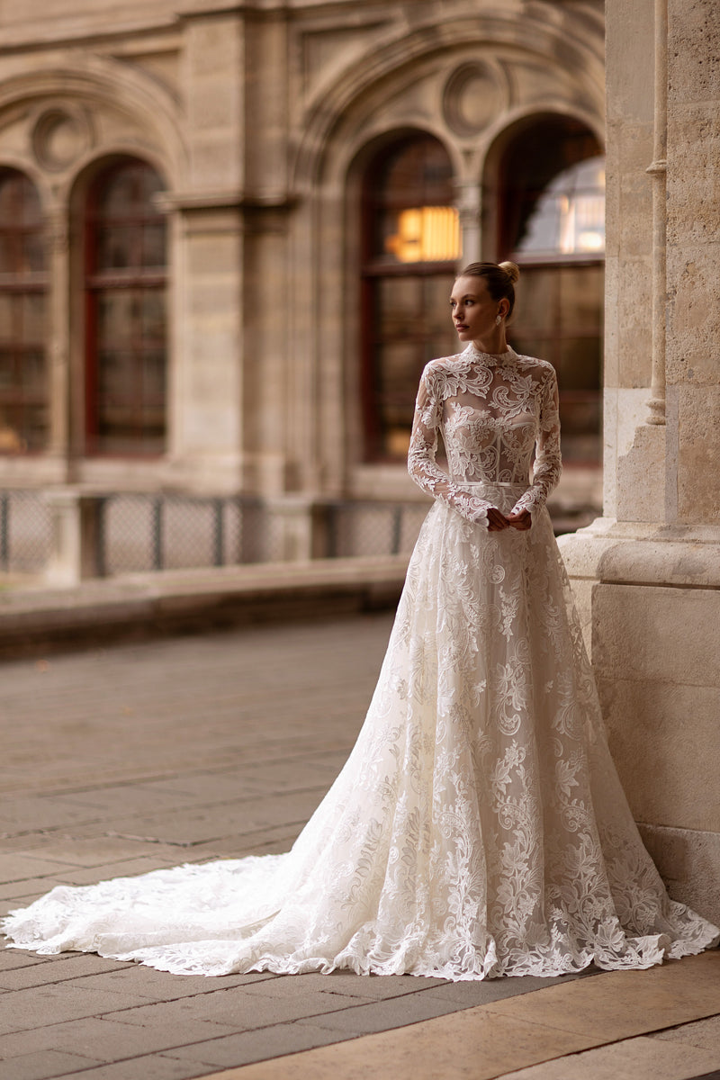Ivory A-line wedding dress with a high neckline, long lace sleeves, floral appliqués, and a sweeping train