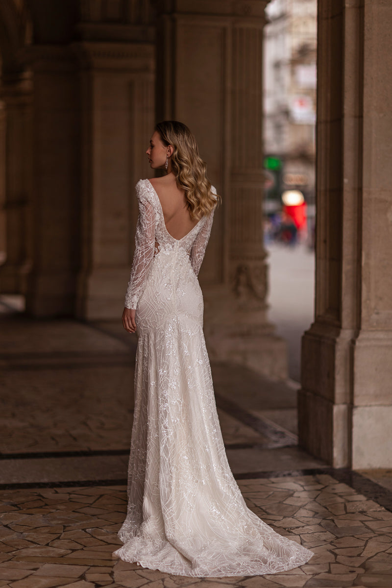 Ivory wedding dress with an open V-back, sheer long sleeves, allover lace, fitted mermaid skirt, and train