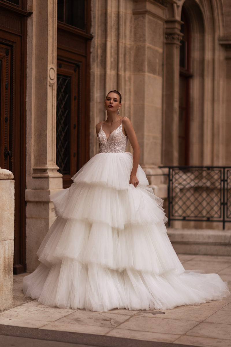 Ivory ball gown wedding dress with a beaded V-neck bodice, thin straps, and tiered tulle skirt