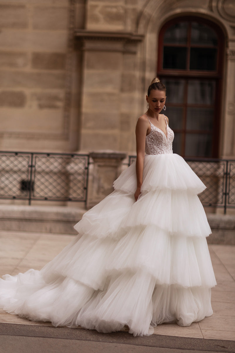 Ivory wedding dress with a lace-appliqué bodice, layered ball gown skirt, and sweeping train