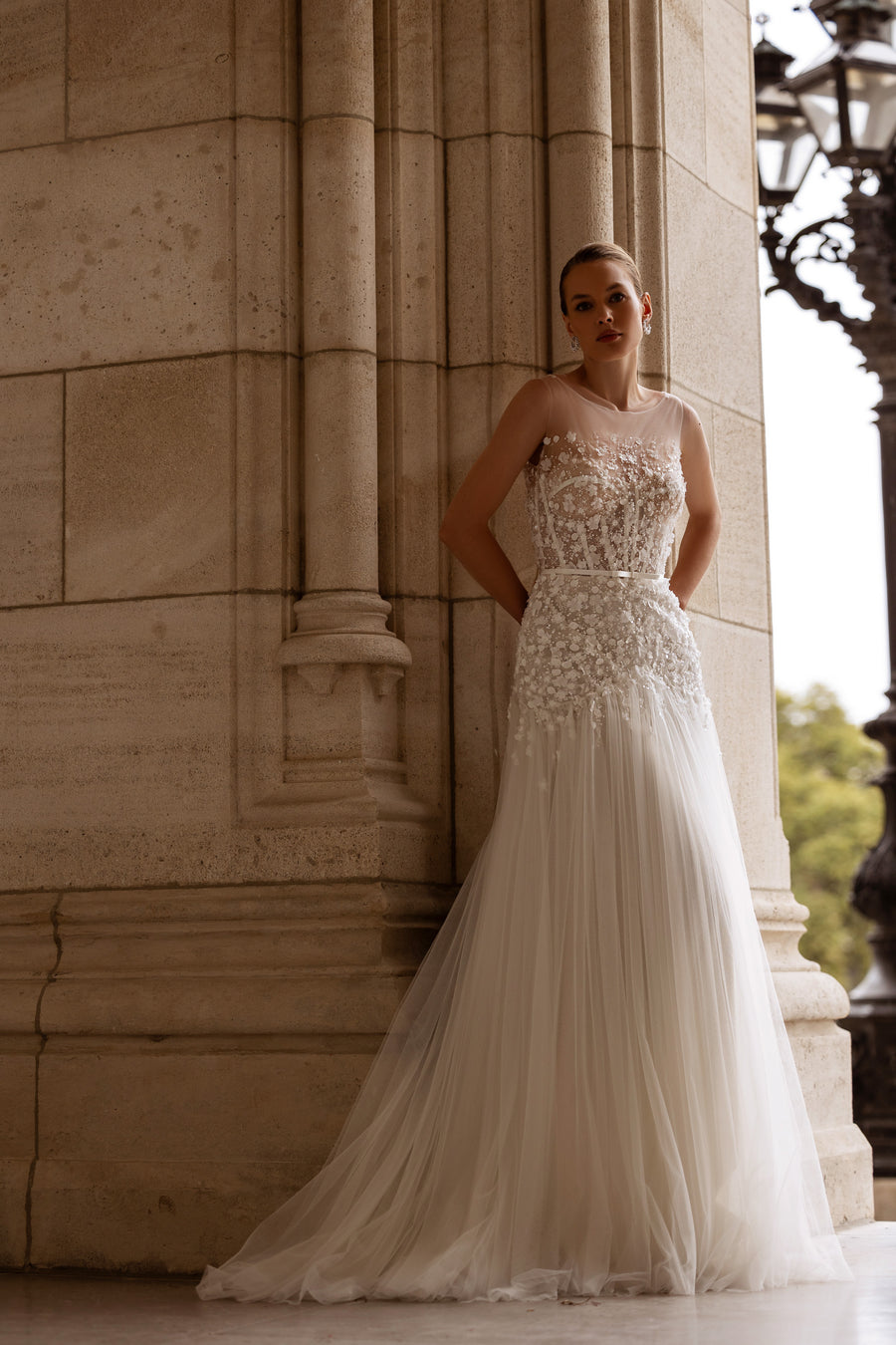 Ivory A-line wedding dress with floral lace bodice, sleeveless neckline, pleated skirt, and train