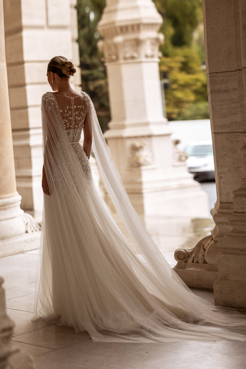 Ivory wedding dress with a floral lace back, sheer draped sleeves, and a long flowing train