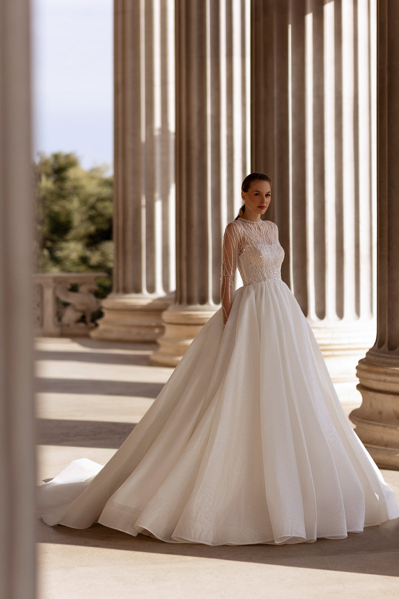 Ivory ball gown wedding dress with a sheer beaded high neckline, long sleeves, and a full sparkling skirt