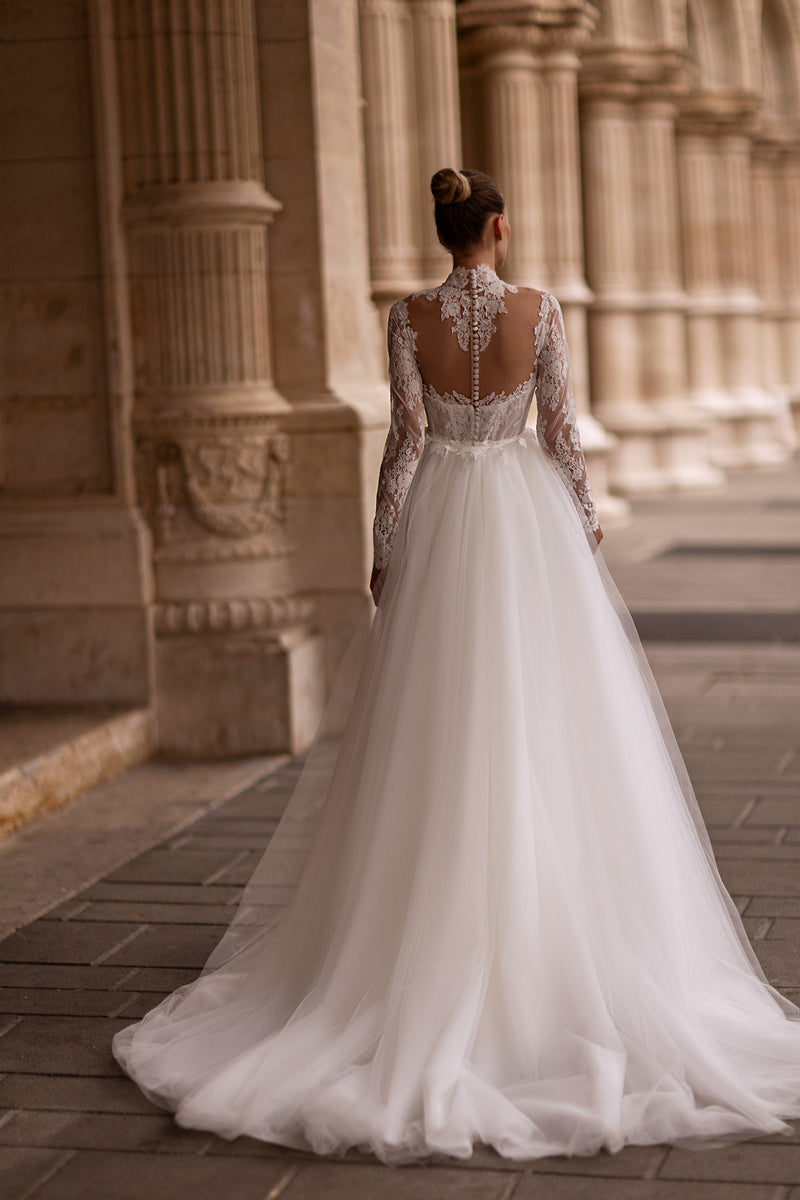Open illusion-lace back with covered buttons and a full tulle train on an ivory wedding dress