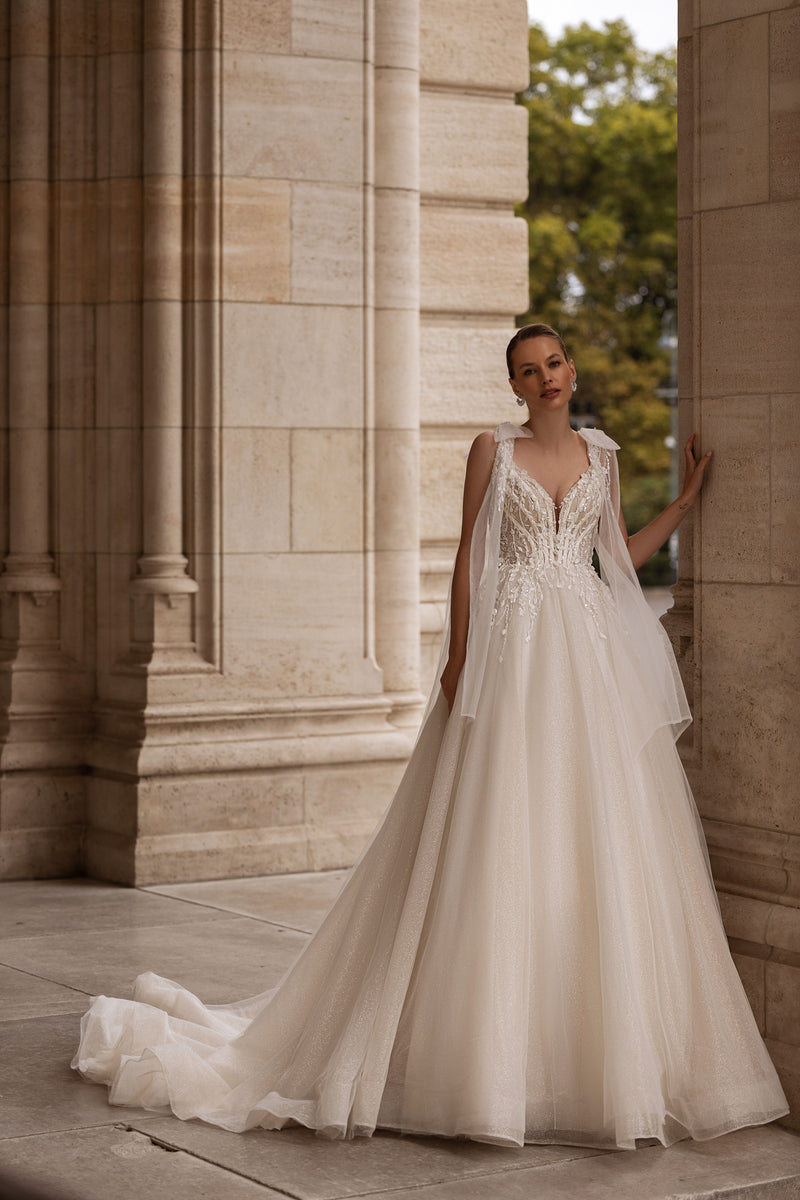 Ivory ball gown wedding dress with a V-neck, floral lace appliqués, sheer sleeves, and a long train