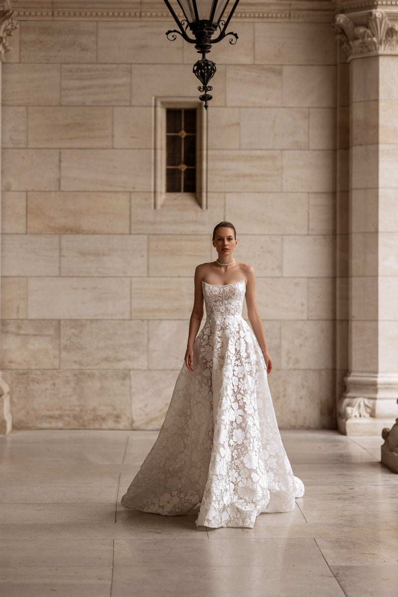 Ivory A-line wedding dress with a strapless neckline, floral lace, and a sweeping train