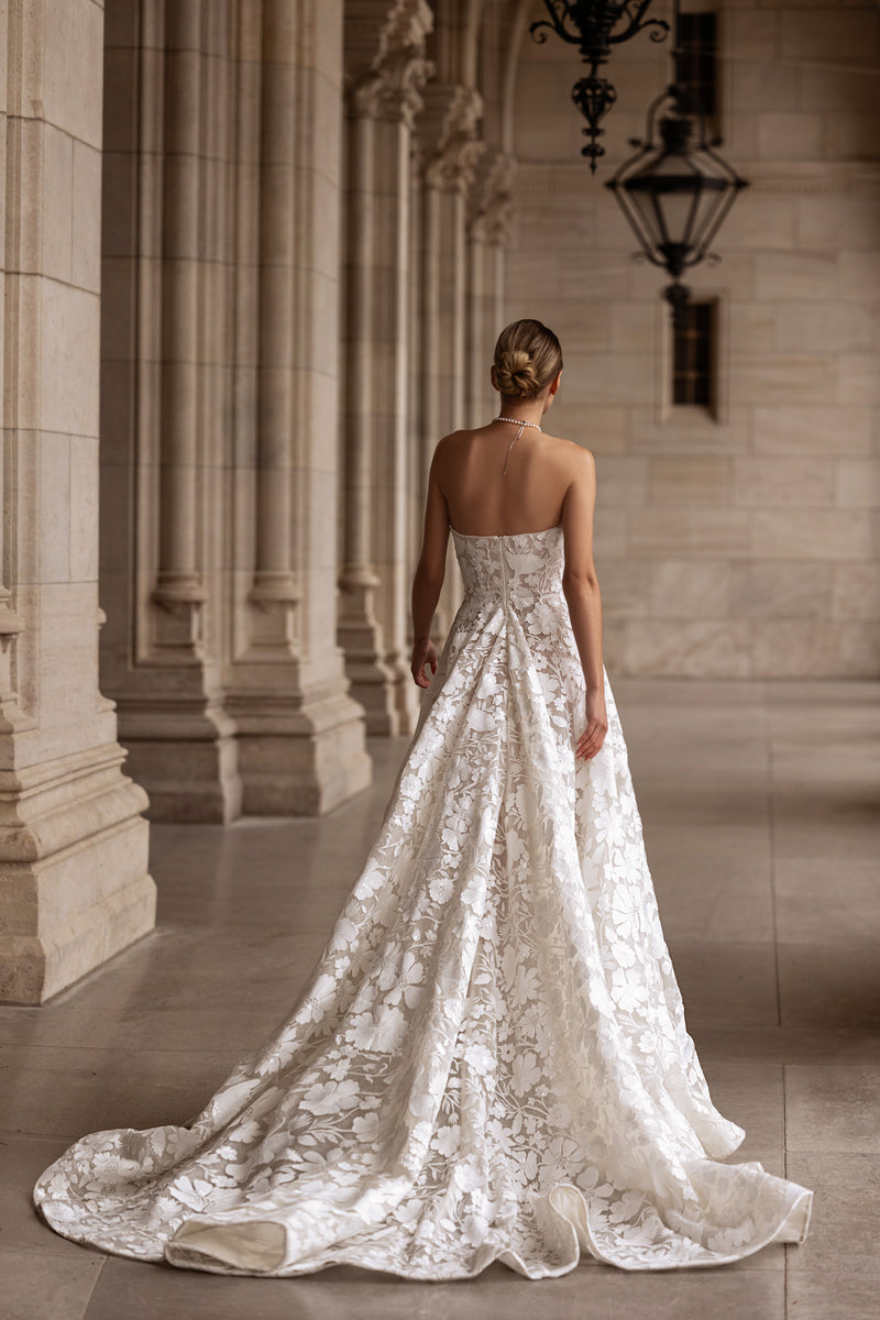 Strapless wedding dress with an open back, floral lace detailing, and a long chapel train