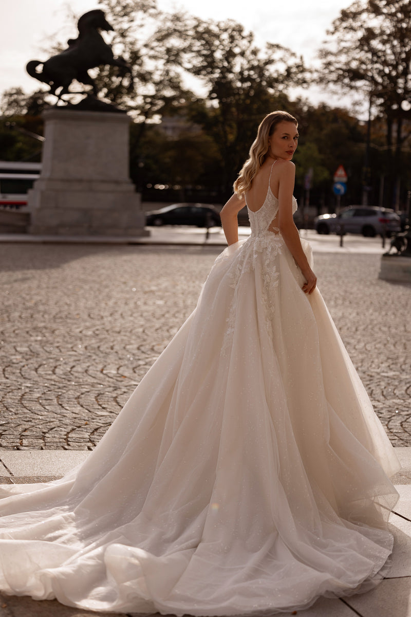 Low open-back ivory wedding dress with lace detailing, a voluminous ball gown skirt, and long train