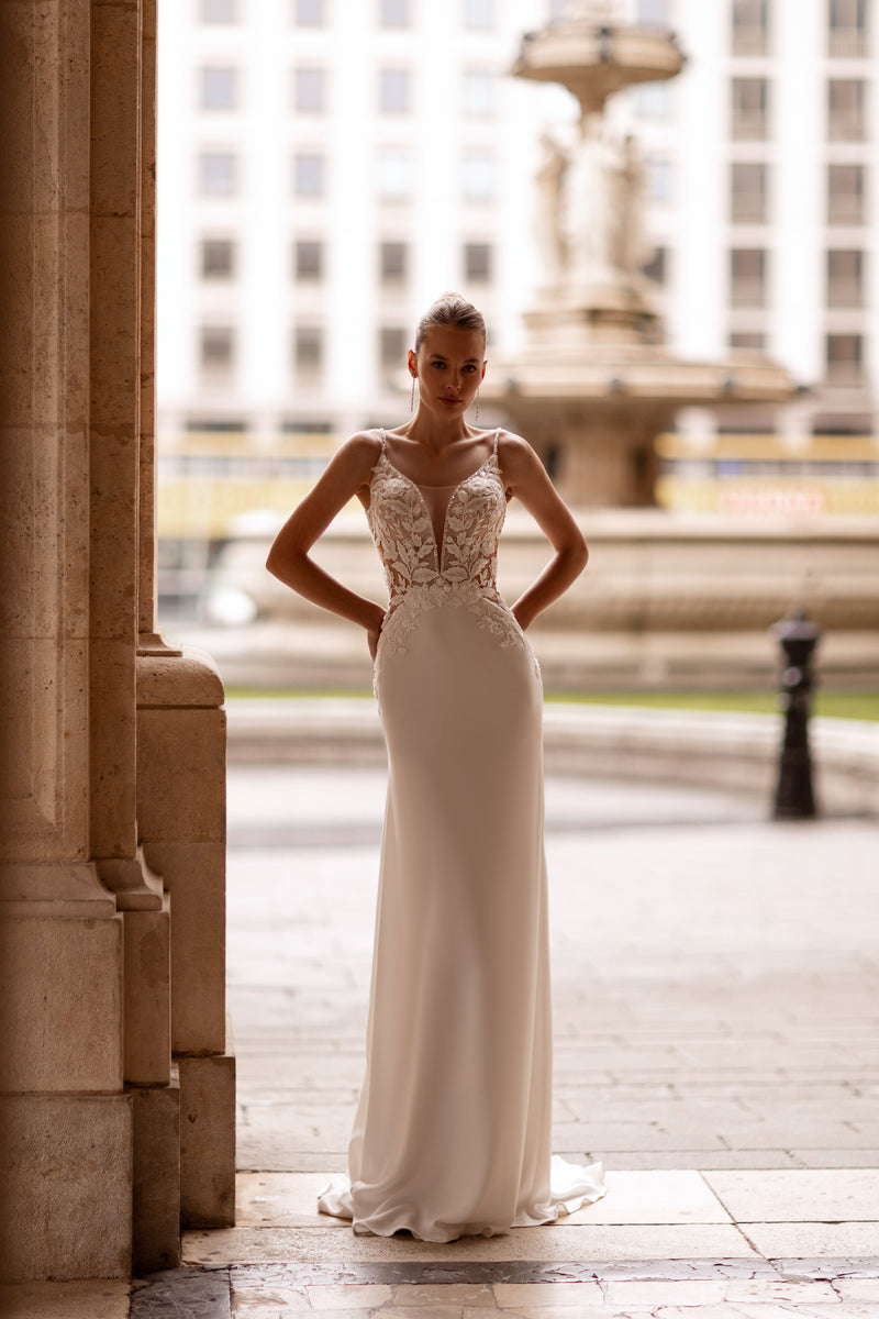 Ivory sheath wedding dress with a plunging V-neckline, floral lace bodice, and delicate straps