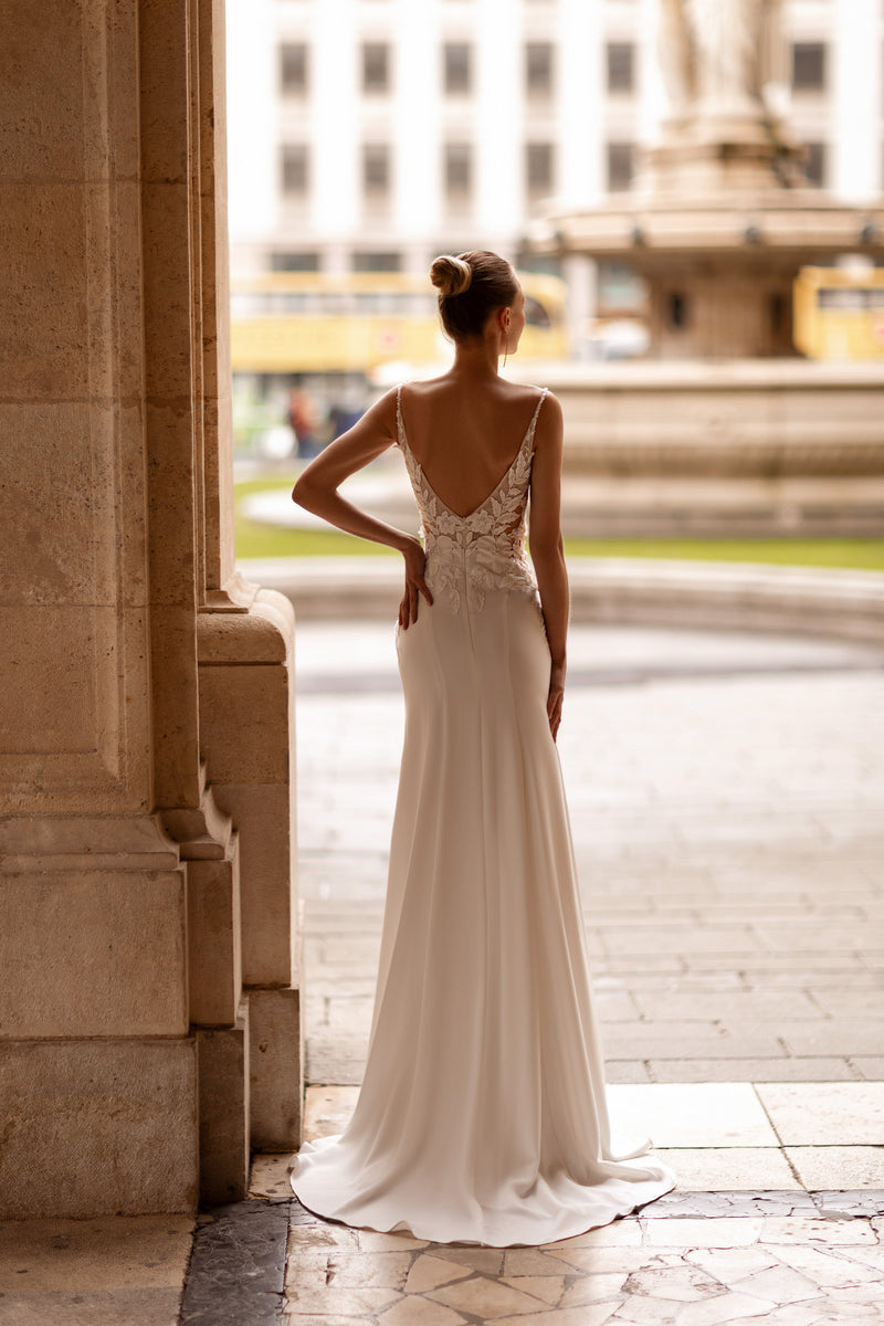 Low V-back wedding dress with floral lace appliqués, slim straps, and a sweeping floor-length train