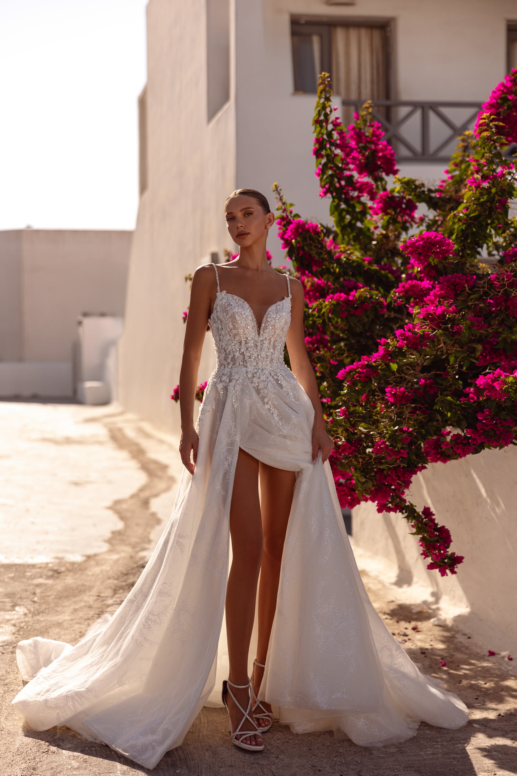Ivory wedding dress with a beaded V-neck bodice, dramatic front slit, flowing overskirt, and train