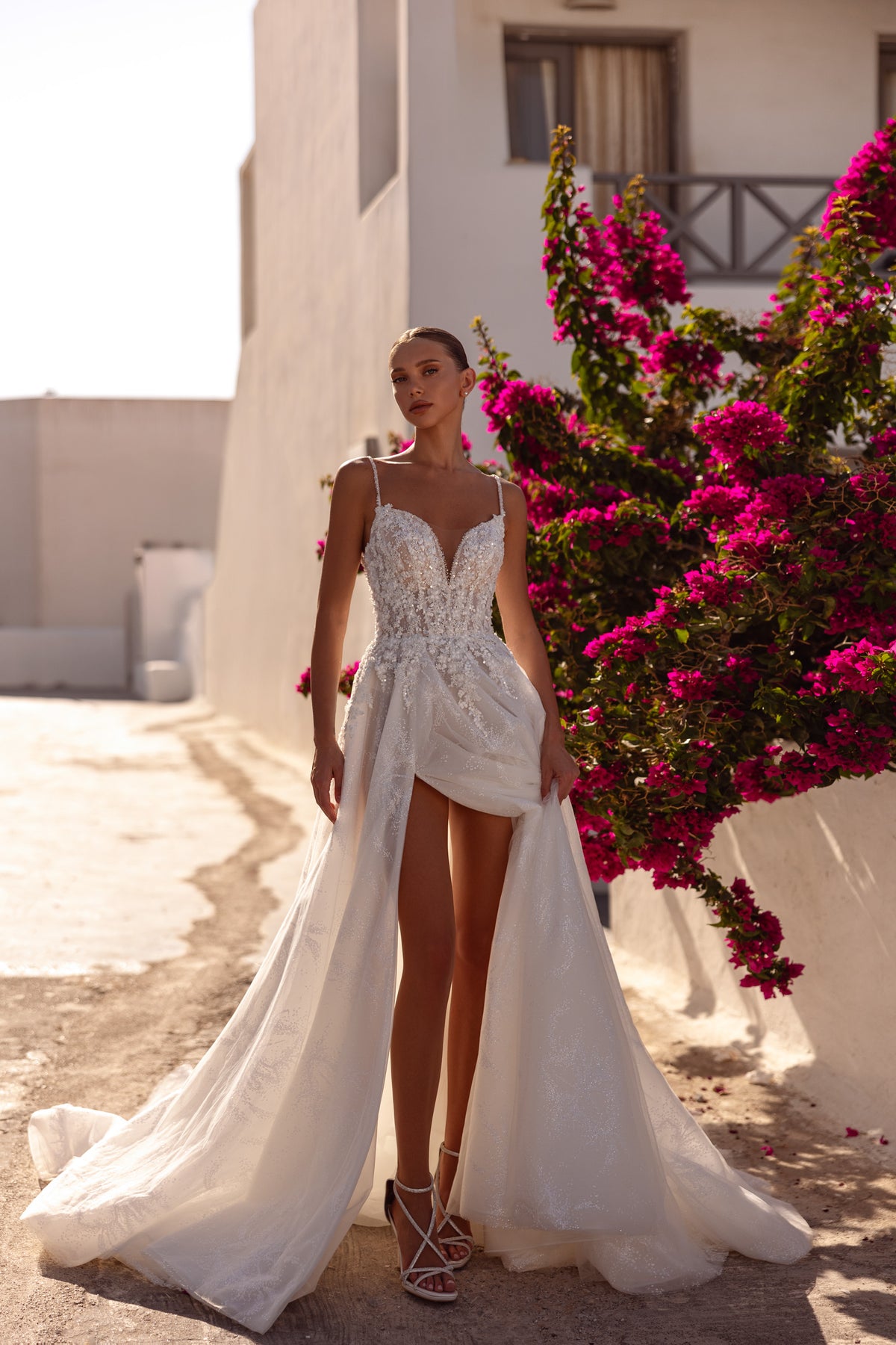 Ivory wedding dress with a beaded V-neck bodice, dramatic front slit, flowing overskirt, and train