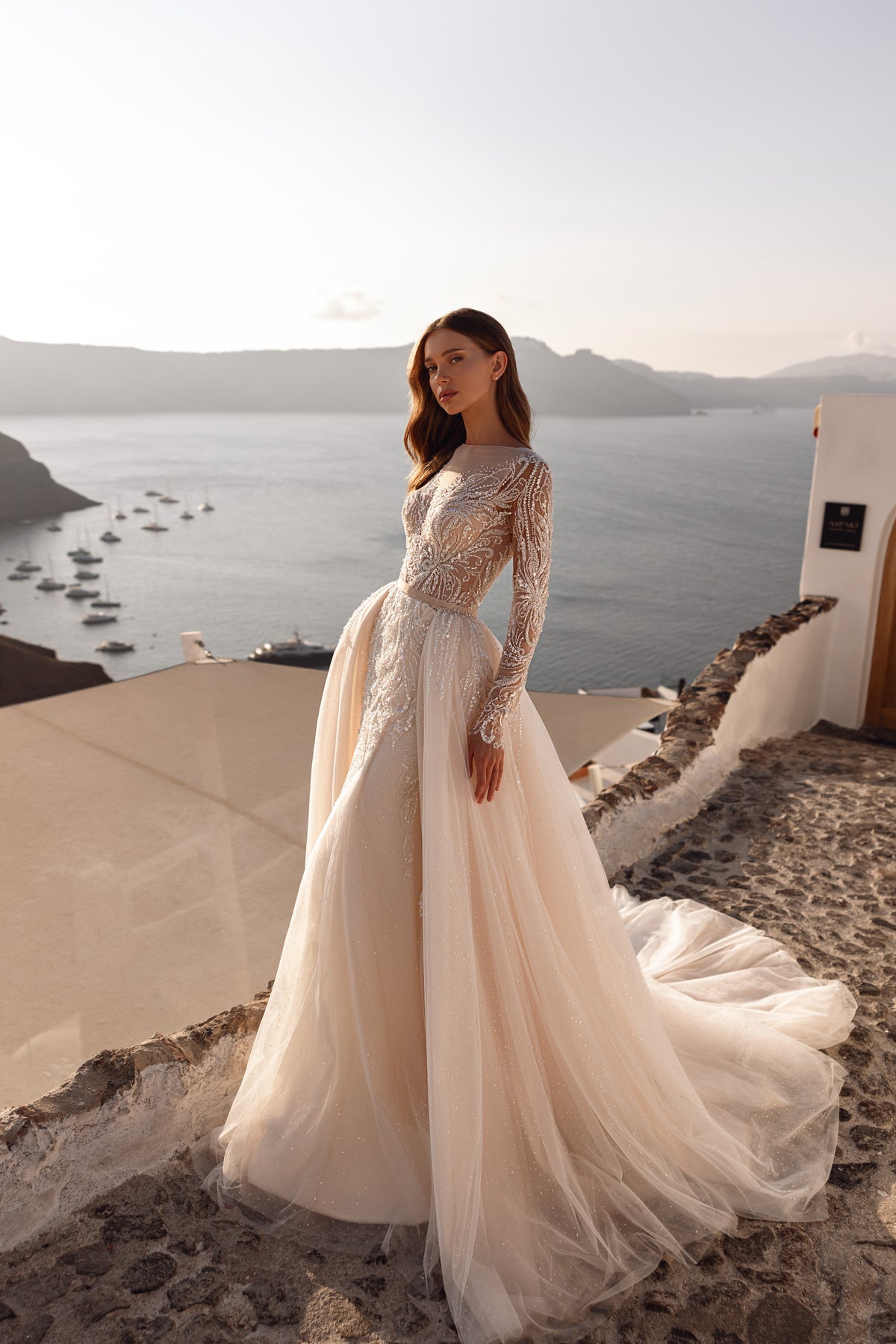 Ivory wedding dress with a fitted beaded bodice, sheer long sleeves, and a full flowing skirt with train